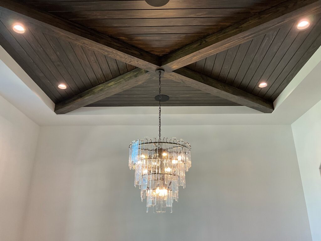 A massive crystal chandelier hanging from a high channeled dark wood ceiling