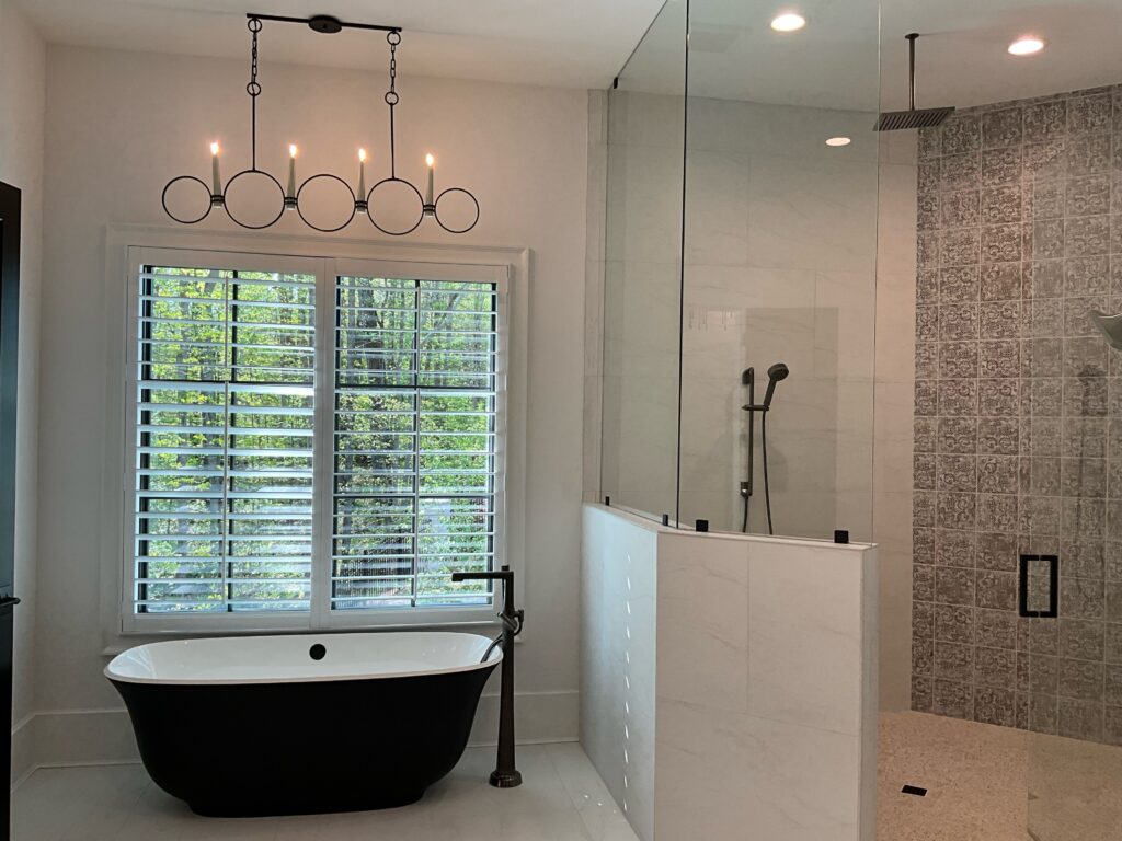 A luxurious bathroom with inset lights in the shower and a unique chandelier with black circles and white candles over the tub